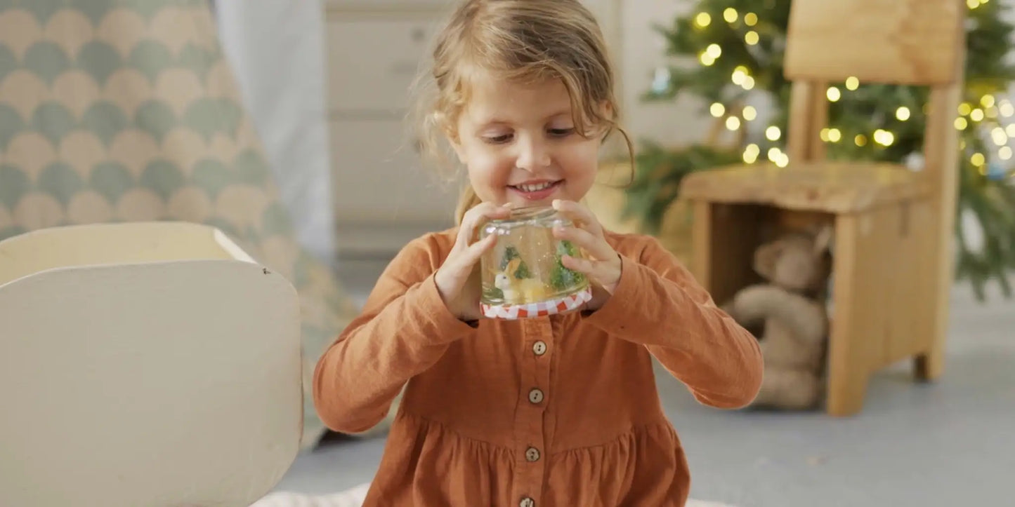 Kind mit DIY Schneekugel in winterlichem Kidnerzimmer