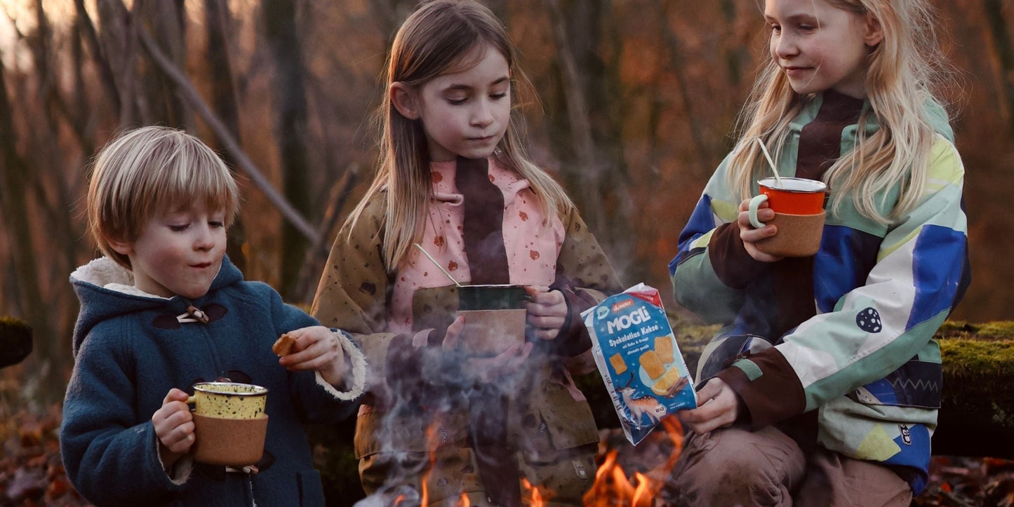 Drei Kinder snacken Kekse am Lagerfeuer