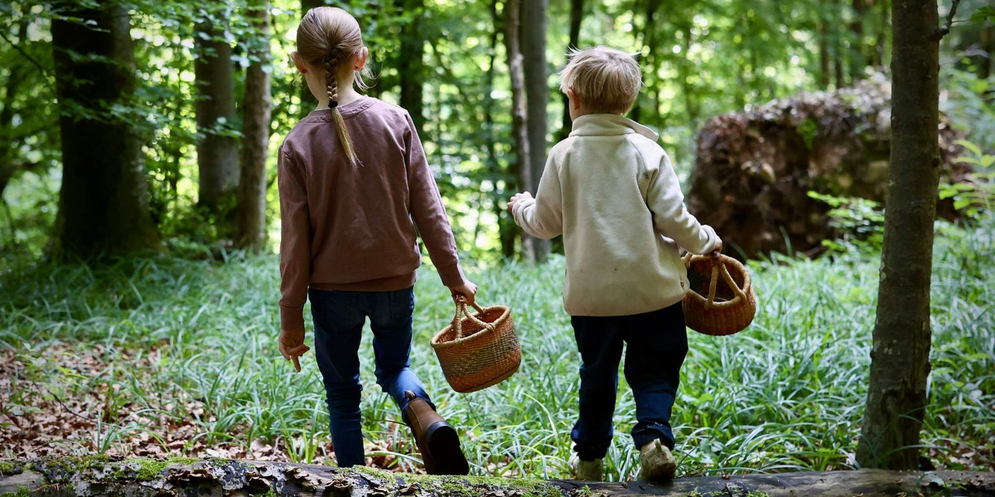 Zwei Kinder im Wald mit Körben in der Hand