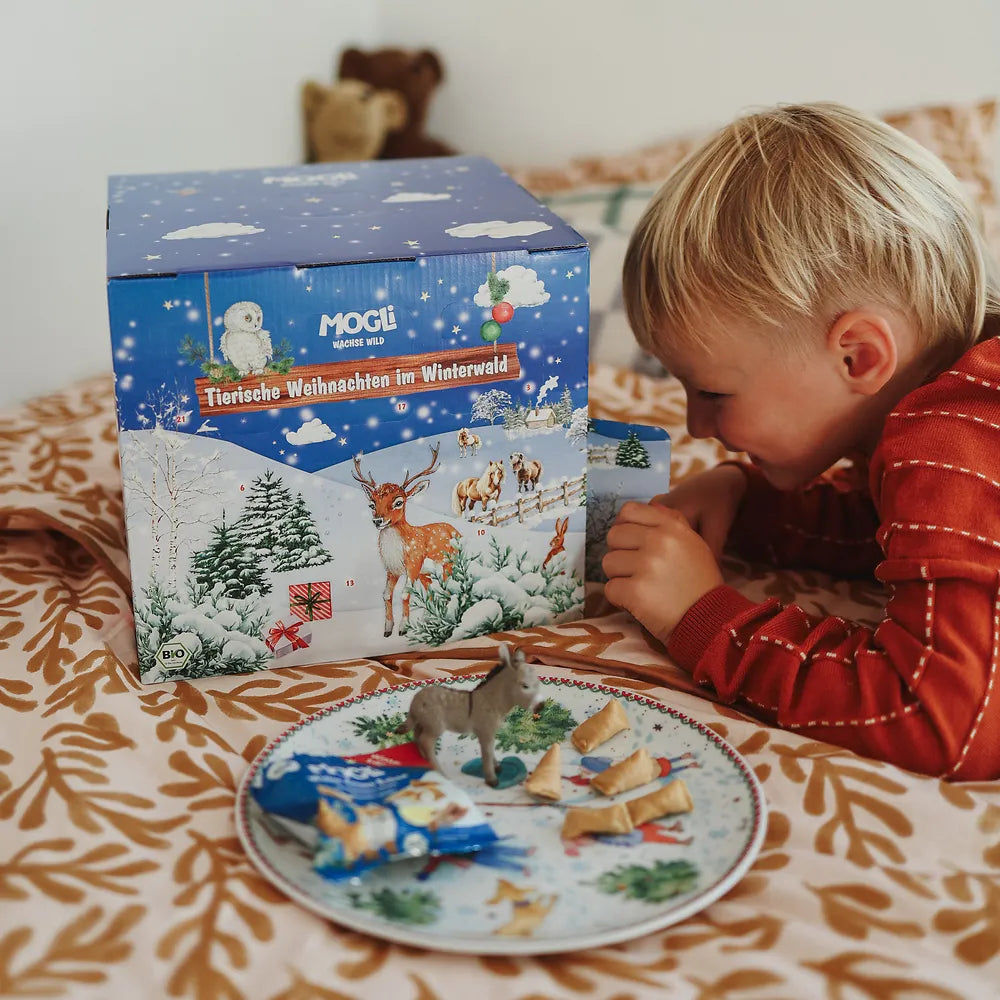 Kind entdeckt den Inhalt des MOGLi Bio-Adventskalenders mit Snack und Esel-Tierfigur.