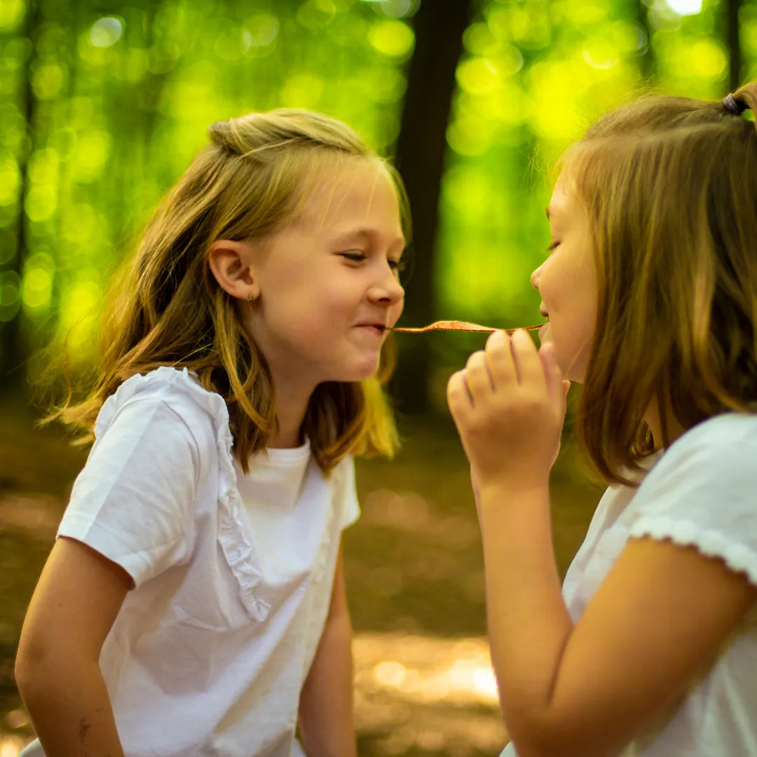 Zwei Mädchen teilen sich im Wald einen Frucht Streifen von MOGLi.