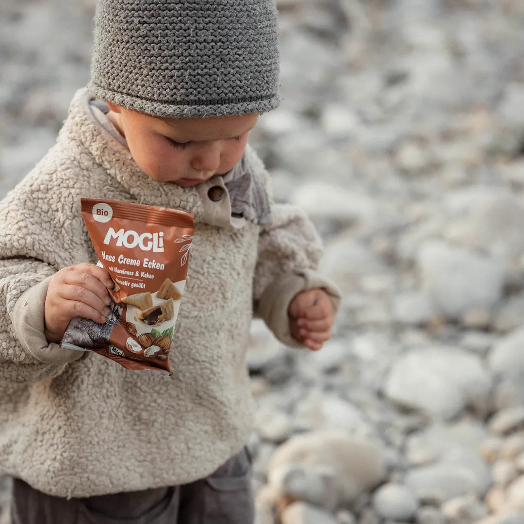 Ein kleiner Junge hält eine Packung MOGLi Nuss Creme Ecken in der Hand