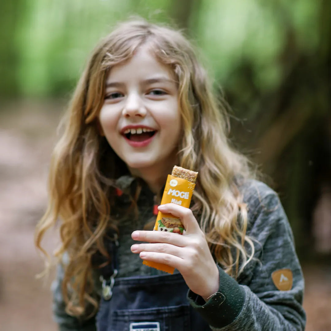 Ein Mädchen hält einen MOGLi Müsli Riegel in der Hand.